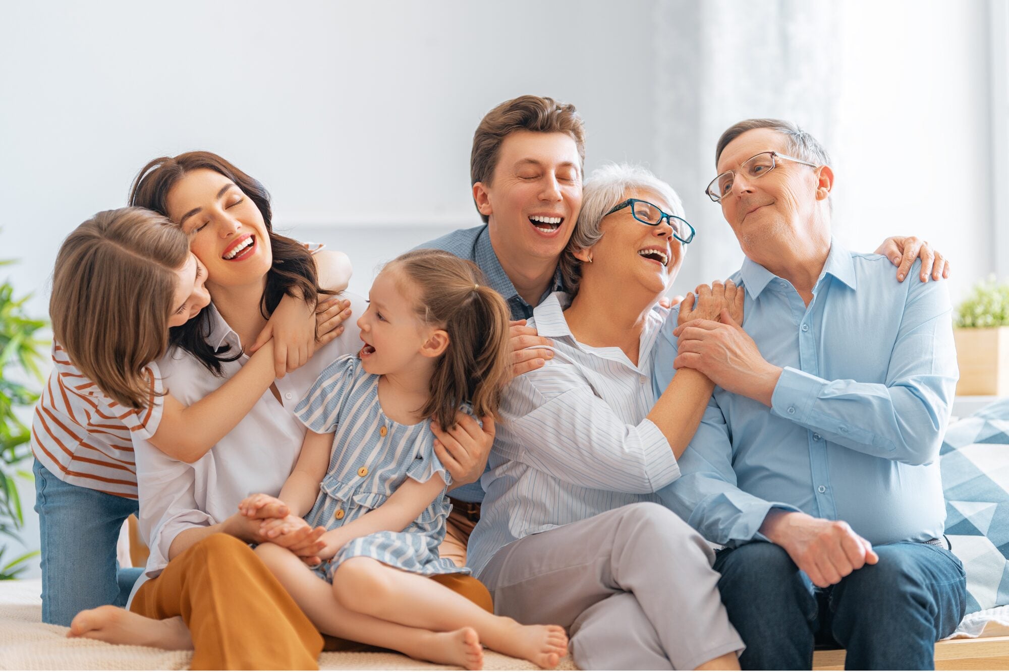 Three generations of a family laughing together on a sofa