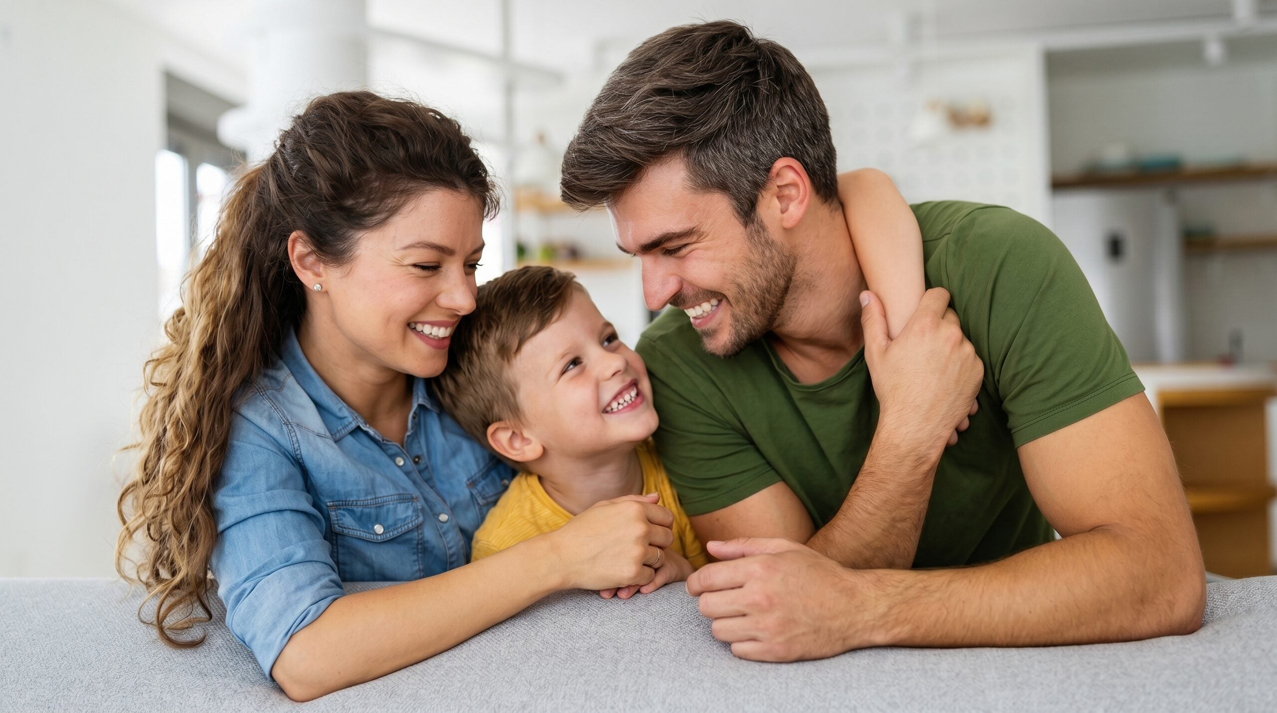 A mother, father and young son laughing together at home